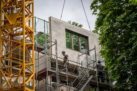 Construction workers installing a prefabricated concrete wall